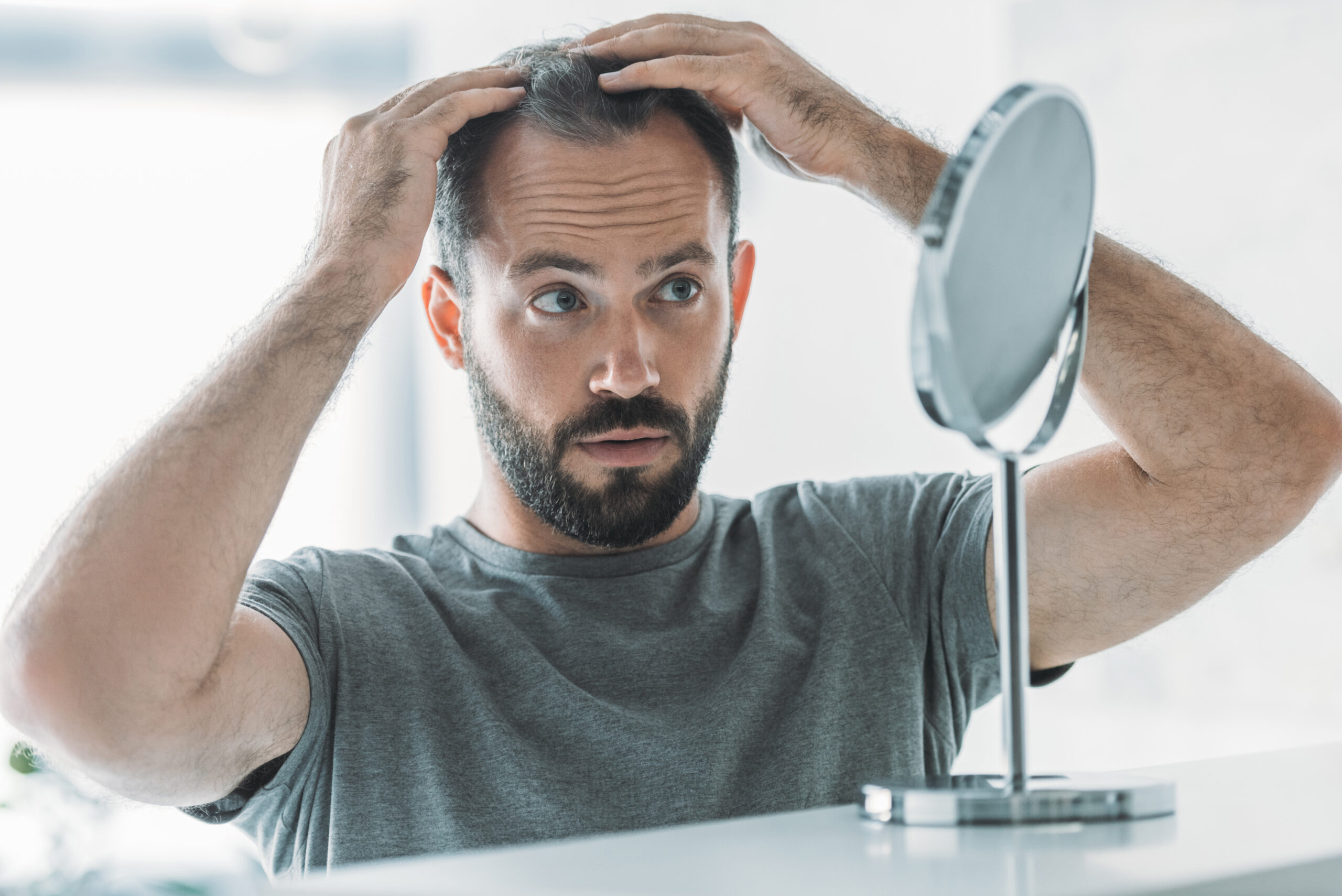man looking at his hair loss in a mirror